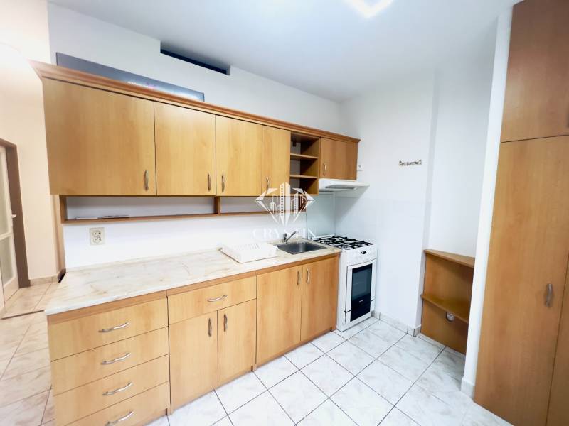 A kitchen in a 2-room apartment with ceramic tiles and wooden cabinets.