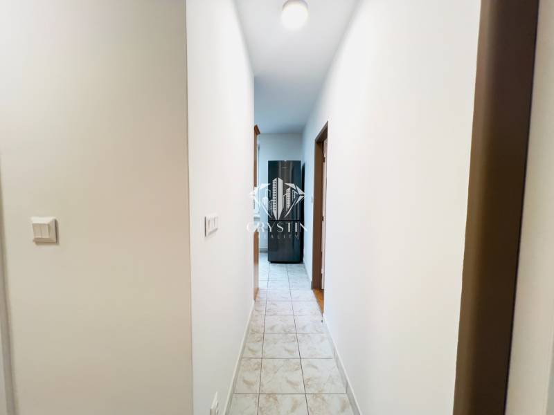 A hallway with tiles leading to the rooms in a 2-room apartment.