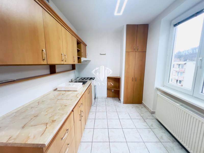A kitchen with wooden decor and white tiles in a 2-room apartment.