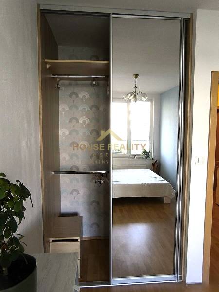 Built-in wardrobe with a mirror, next to the room with a bed in a 2-room apartment.