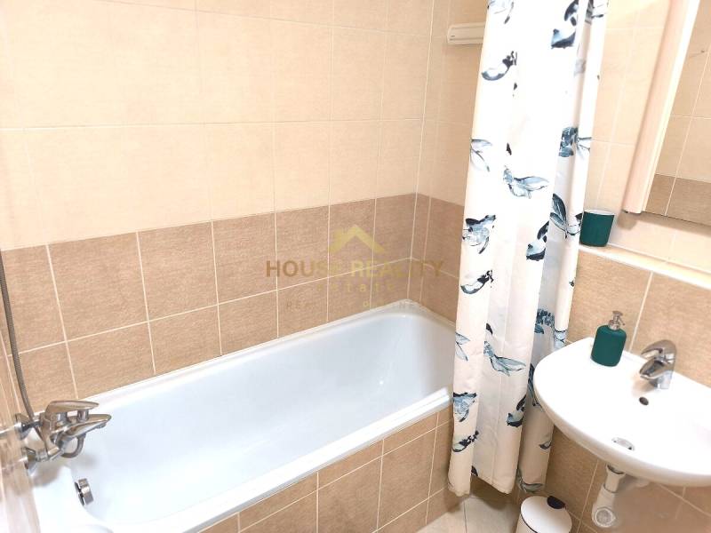 Bathroom in a 2-room apartment with a bathtub, sink, and bathroom tiles.