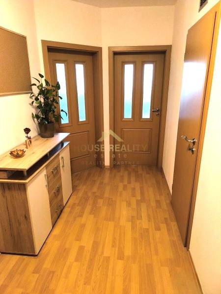 A hallway in a 2-room apartment with a wooden decor floor and wooden furniture.