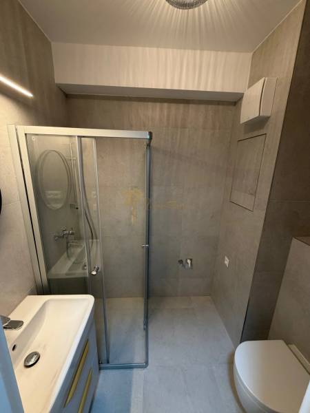 Compact bathroom with a modern shower and mirror in a studio apartment.