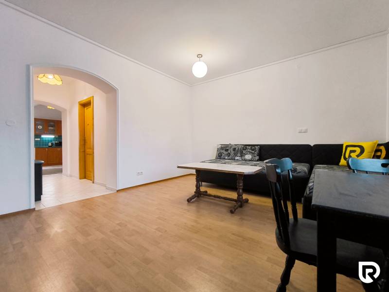 Living room in a family house with a wooden decor floor, sofa, and dining table.