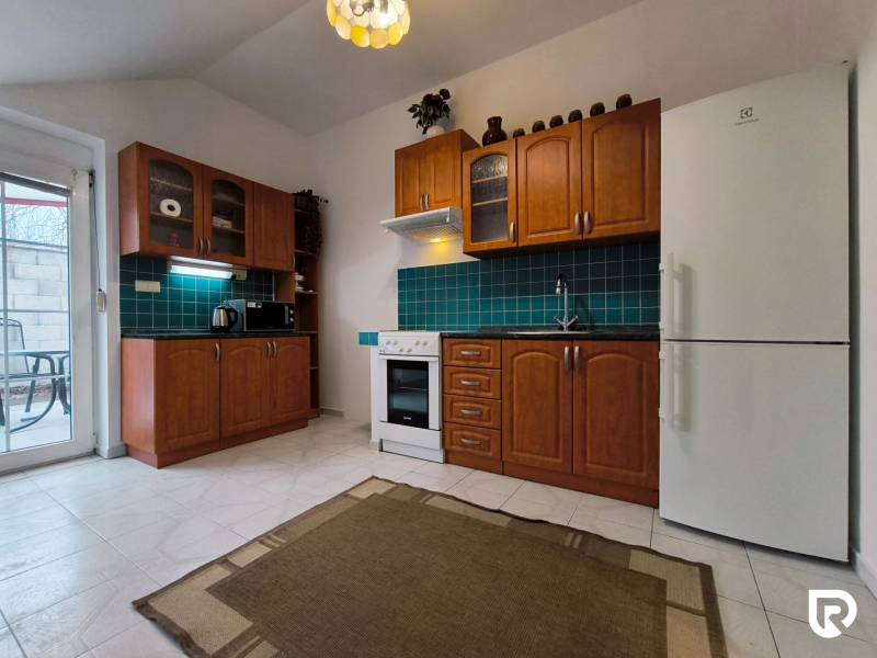 A kitchen with wooden cabinets and green tiles in a family house.