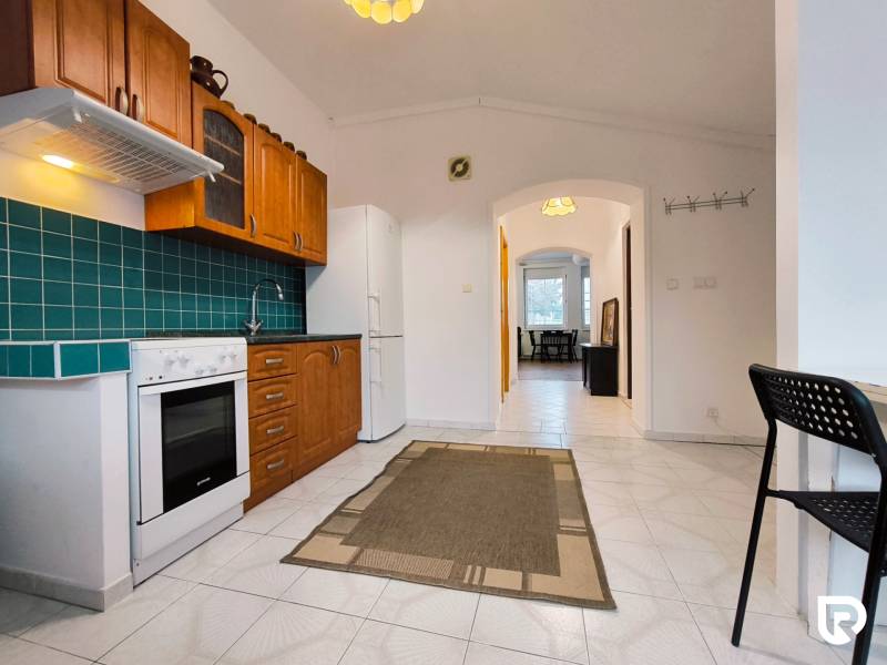 A kitchen in a family house with white tiles, wooden decor, and blue tiles.