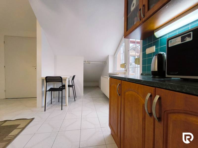 A kitchen in a family house with wooden cabinets, a table, and two black chairs.