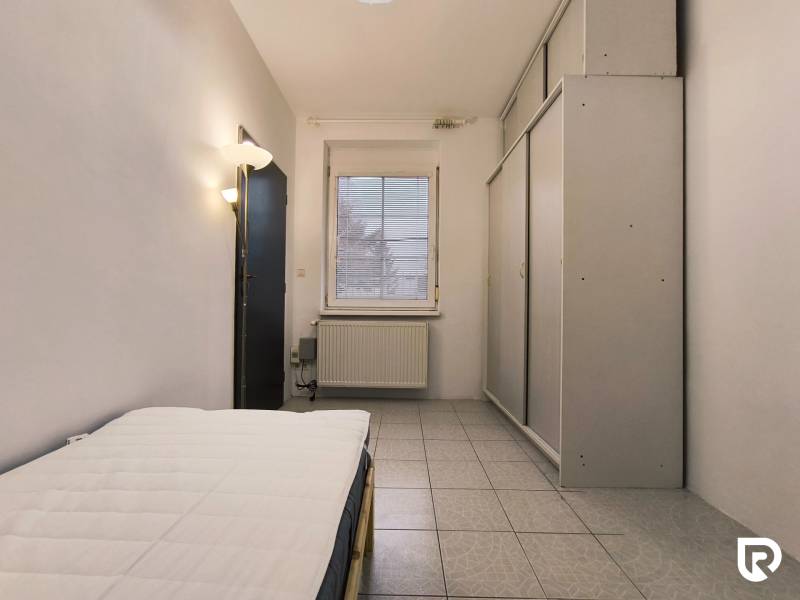 A bedroom in a family house with a bed, a built-in wardrobe, and tiles.
