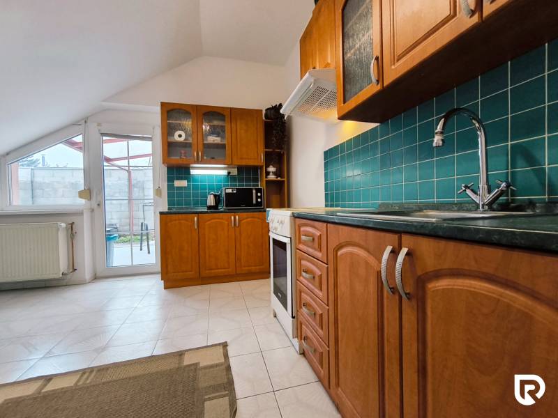 A kitchen with wooden cabinets and green tiles in a family house.