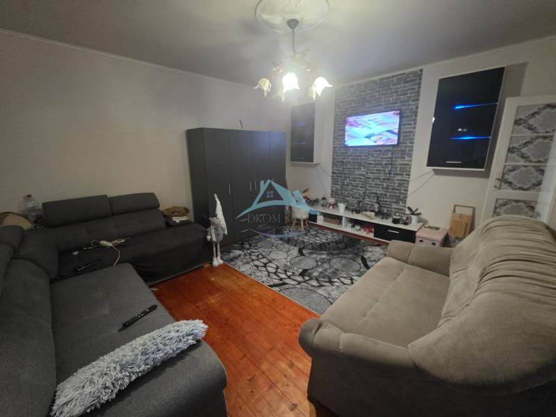 Living room with two sofas, a TV on the wall, and a wooden decor floor.