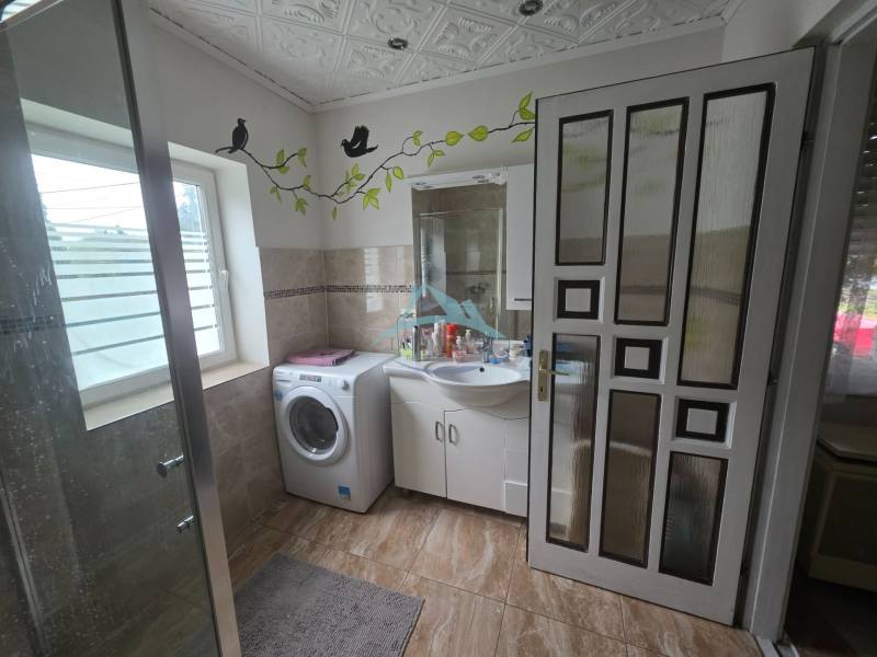 Bathroom with a washing machine, sink, shower corner, and wall decorations in a family house.