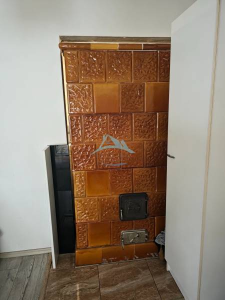 Tiled stove in a family house with a wood-patterned floor.