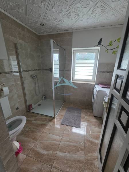 A bathroom in a family house with a toilet, shower, and washing machine.