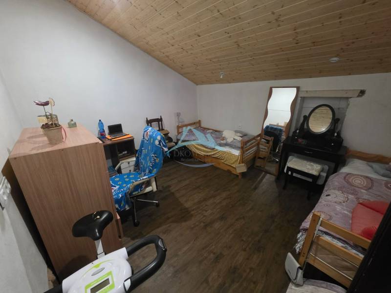 Attic room with a wooden ceiling, wooden decor flooring, bed, table, mirror.
