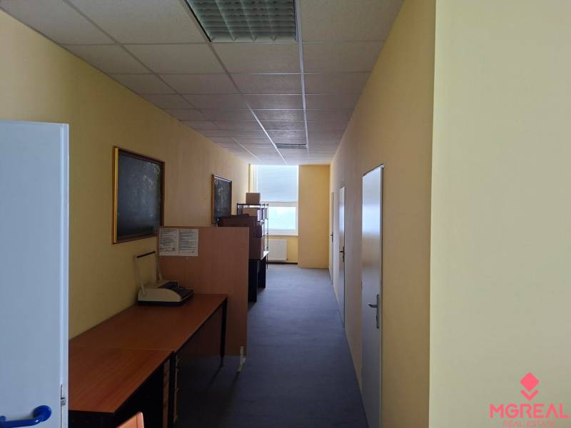 Offices with narrow corridor space, desks, and wall decorations.