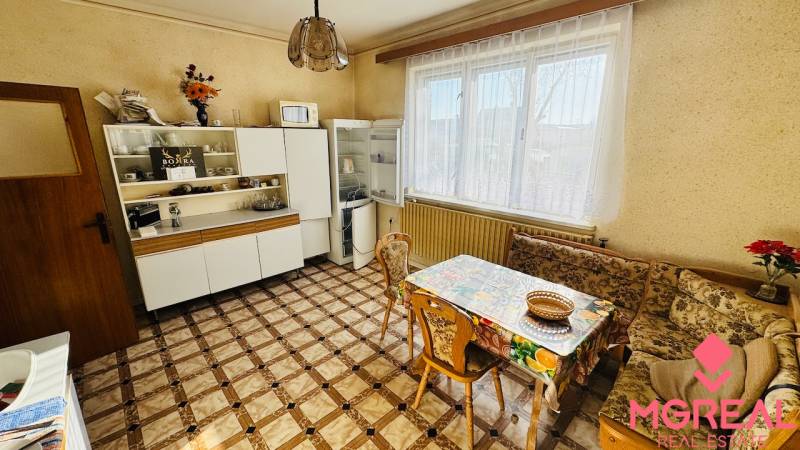 A kitchen in a family house with a dining area, a cabinet, and a refrigerator.