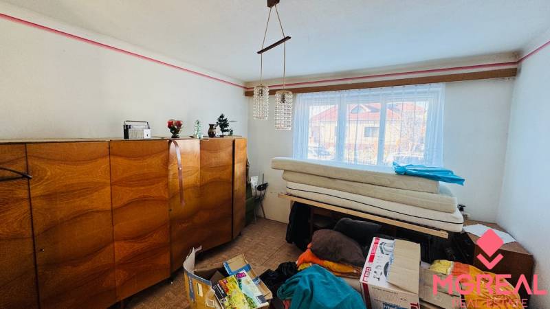A room in a family house with wooden furniture, a chandelier, and a window with a view.