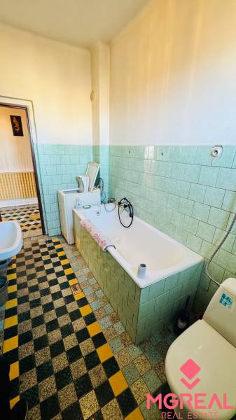 Bathroom in a family house with a bathtub, sink, and light green tiles.