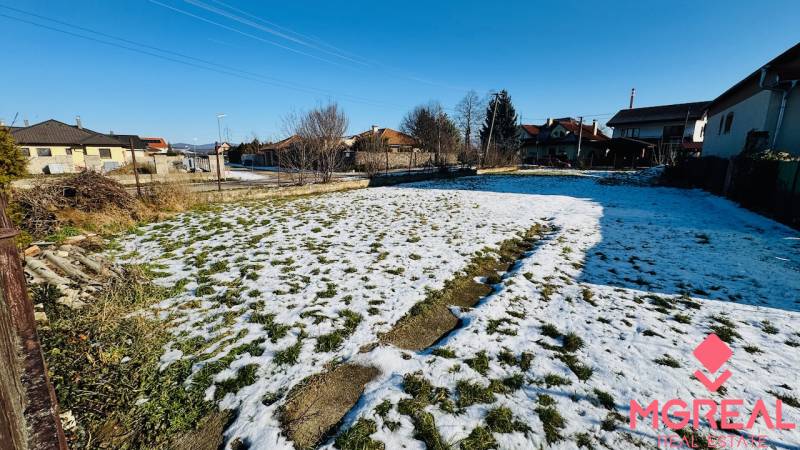 A snow-covered plot of land behind a family house in Veľké Bielice in Partizánske, surrounded by houses.