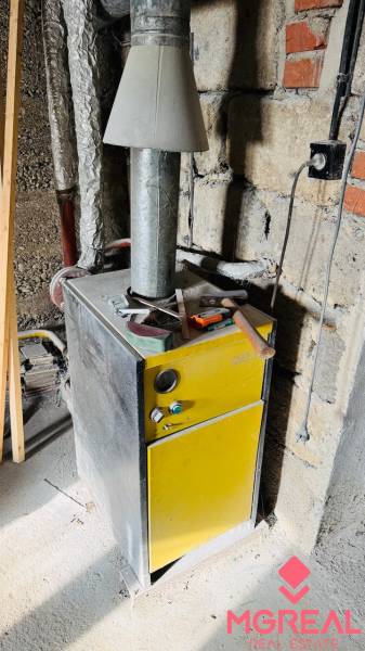 Boilers in a family house, with tools on top, in an unfinished room.
