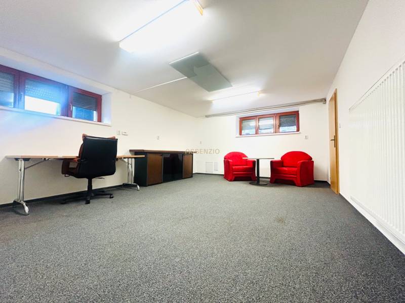 The office in the family house has a carpet, a desk, and red chairs.
