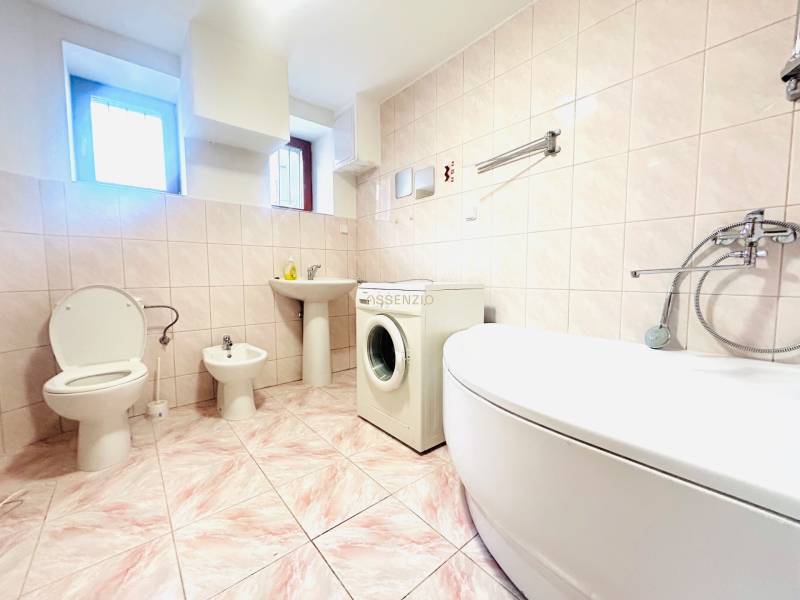 A bathroom in a family house with a bathtub, toilet, bidet, and washing machine.