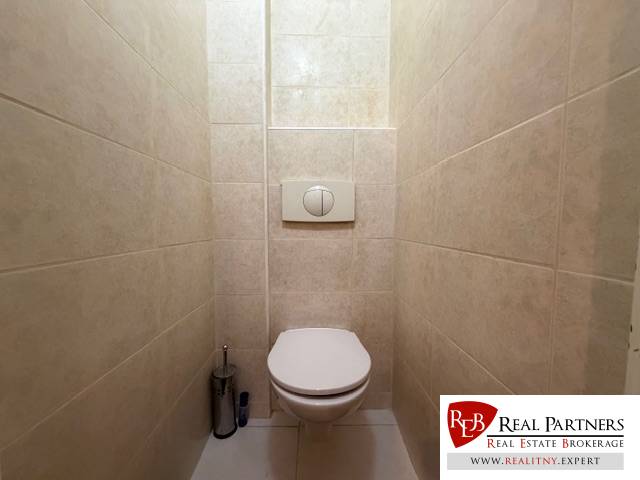 A toilet with white tiles and a built-in toilet in a 3-room apartment.