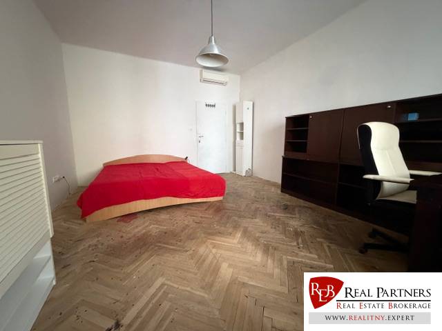 A room with a bed, a desk, and a floor with a wooden decor in a 3-room apartment.