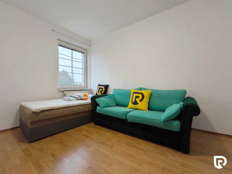 A room with a sofa and a bed, a floor with a wooden decor, a family house.