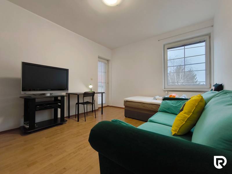 Living room in a family house with a sofa, television, table, and wooden decor flooring.
