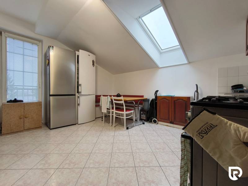 A kitchen in a family house with a sloped ceiling, a large refrigerator, and a dining table.