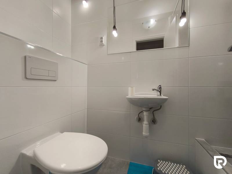 Bathroom in a family house with a wall-mounted toilet, sink, and lights.