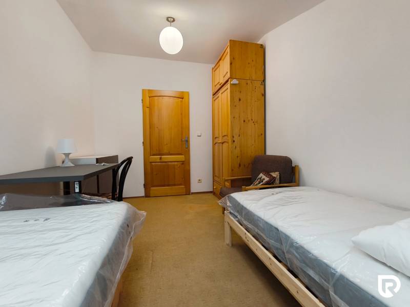 A room in a family house with beds, a table, a wardrobe, and a chair.