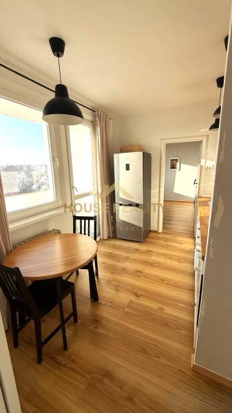 A kitchen with a wooden decor floor and a dining table in a 3-room apartment.