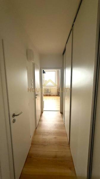 A hallway in a 3-room apartment with a wooden decor floor and white doors.