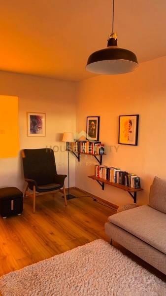 Living room in a 3-room apartment with an armchair, bookshelves, and a wooden decor floor.