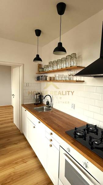 A kitchen with white cabinets, a wooden countertop, and a floor with a wood design.