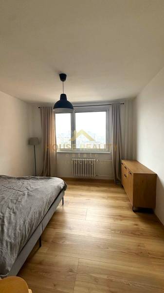 Bedroom with wood-patterned flooring, dresser, and bed in a 3-room apartment.