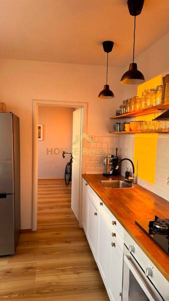 A kitchen in a 3-room apartment with light furniture and a wooden decor floor.