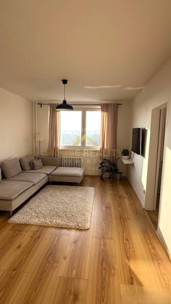 Living room in a three-room apartment with a wooden decor floor and a light sofa.
