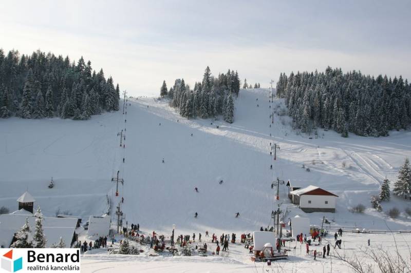 Ski resort on recreational grounds in Litmanová with skiers and snow-covered forests.