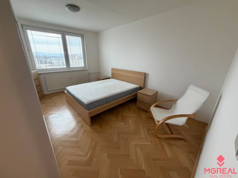 Bedroom with a bed, chair, and view. Floor with wood decor in a 3-room apartment.
