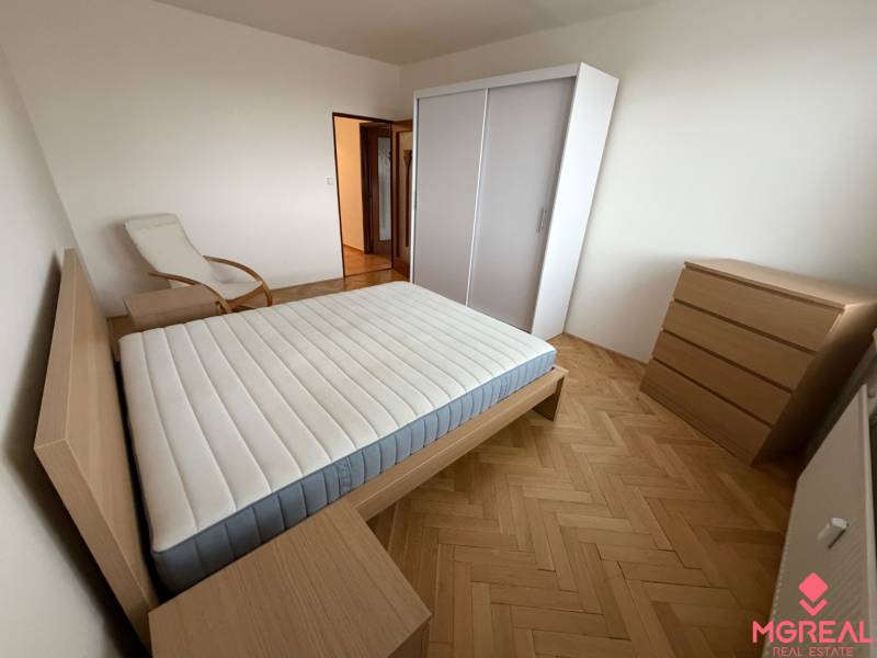 Bedroom with a bed and wooden decor flooring in a 3-room apartment.