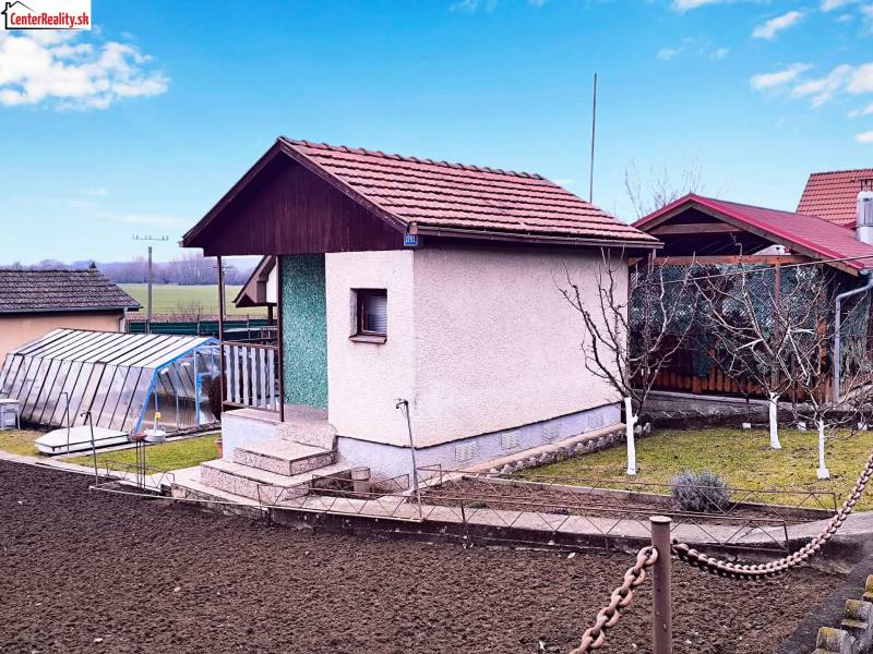 A cottage in Partizánske with a landscaped garden, greenhouse, and cultivation area.