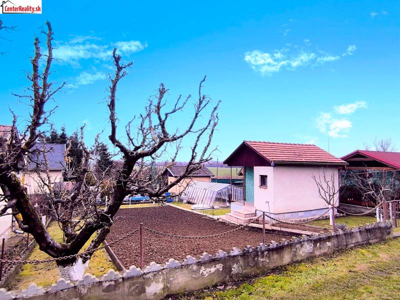 A cottage in Partizánske with a landscaped yard, garden, and leafless trees.