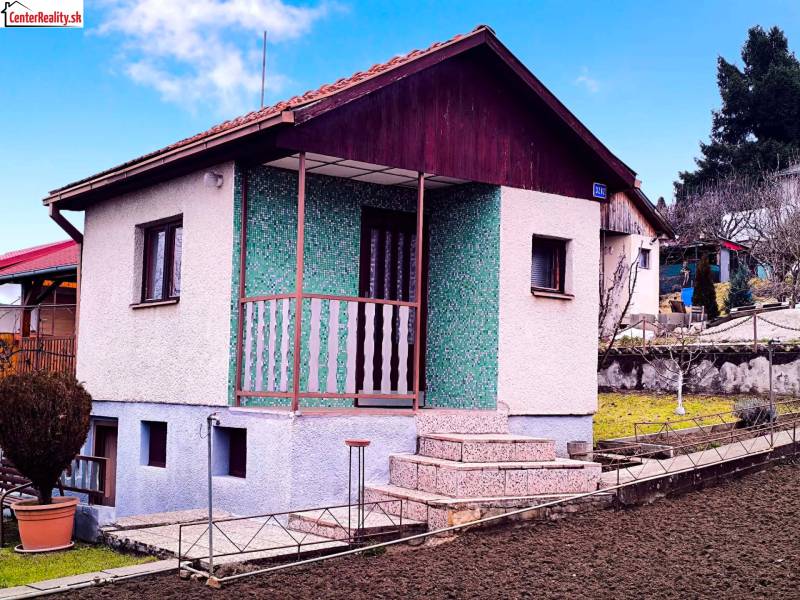 A cottage in Partizánske with landscaped grounds, a green facade, and a staircase to the terrace.