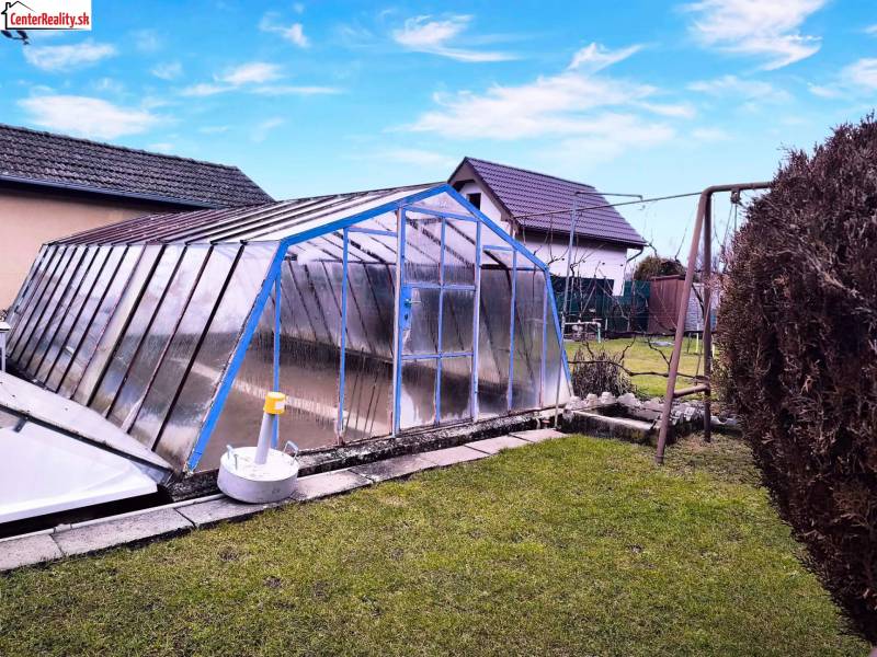 A garden in Partizánske with an above-ground pool covered by a structure, a swing, green lawn.
