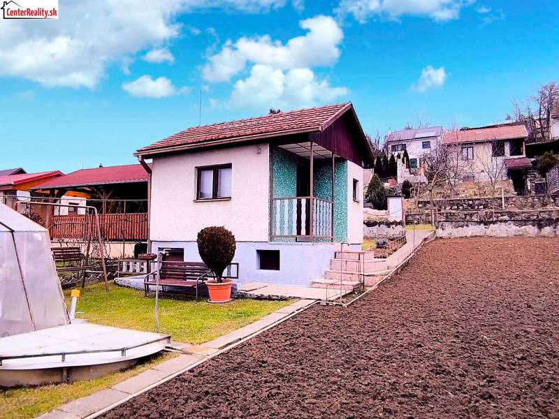 A cottage in Partizánske with a simple garden, curbs, and a gazebo under the blue sky.