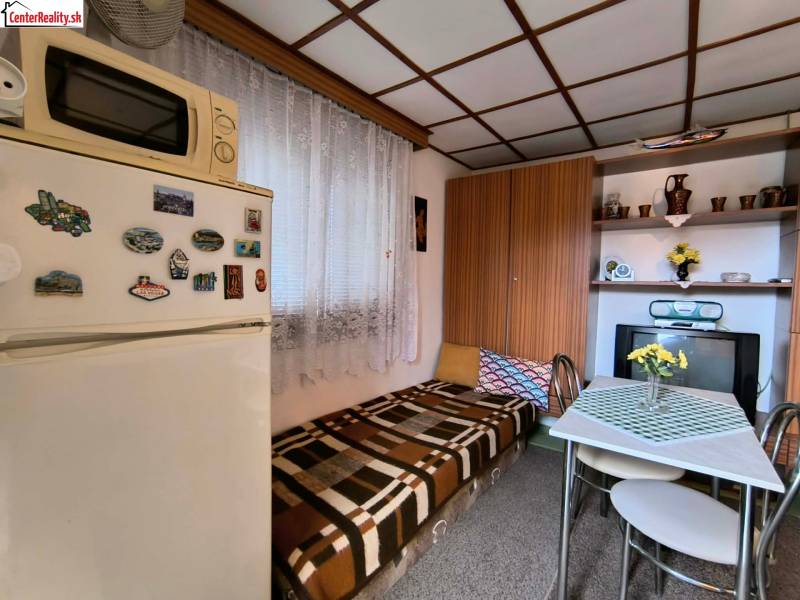 A small kitchen in a cottage with a wooden decor, a dining table, and a refrigerator.