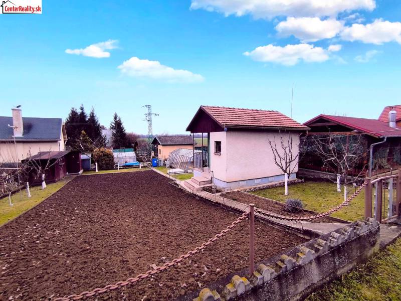 The exterior of the cottage in Partizánske with a landscaped garden, lawn, and flower bed.